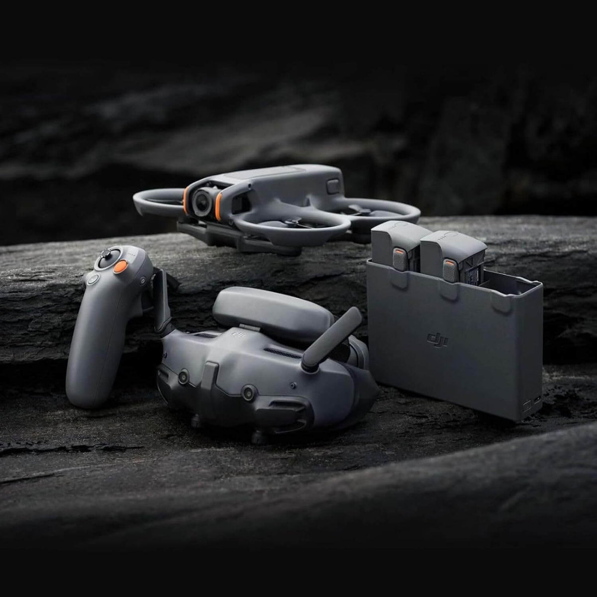 Avata 2 drone, FPV goggles, multiple batteries and remote controller on a dark surface with a blurred natural background