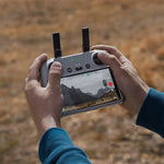 Person holding an RC 2 drone controller with a screen displaying a mountainous landscape