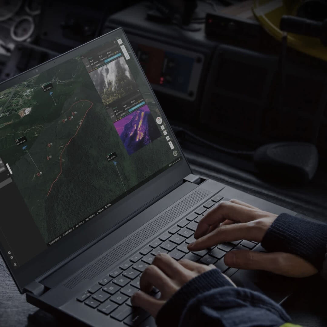 Person using a laptop with a dark-themed software interface inside a vehicle