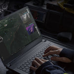 Person using a laptop with a dark-themed software interface inside a vehicle