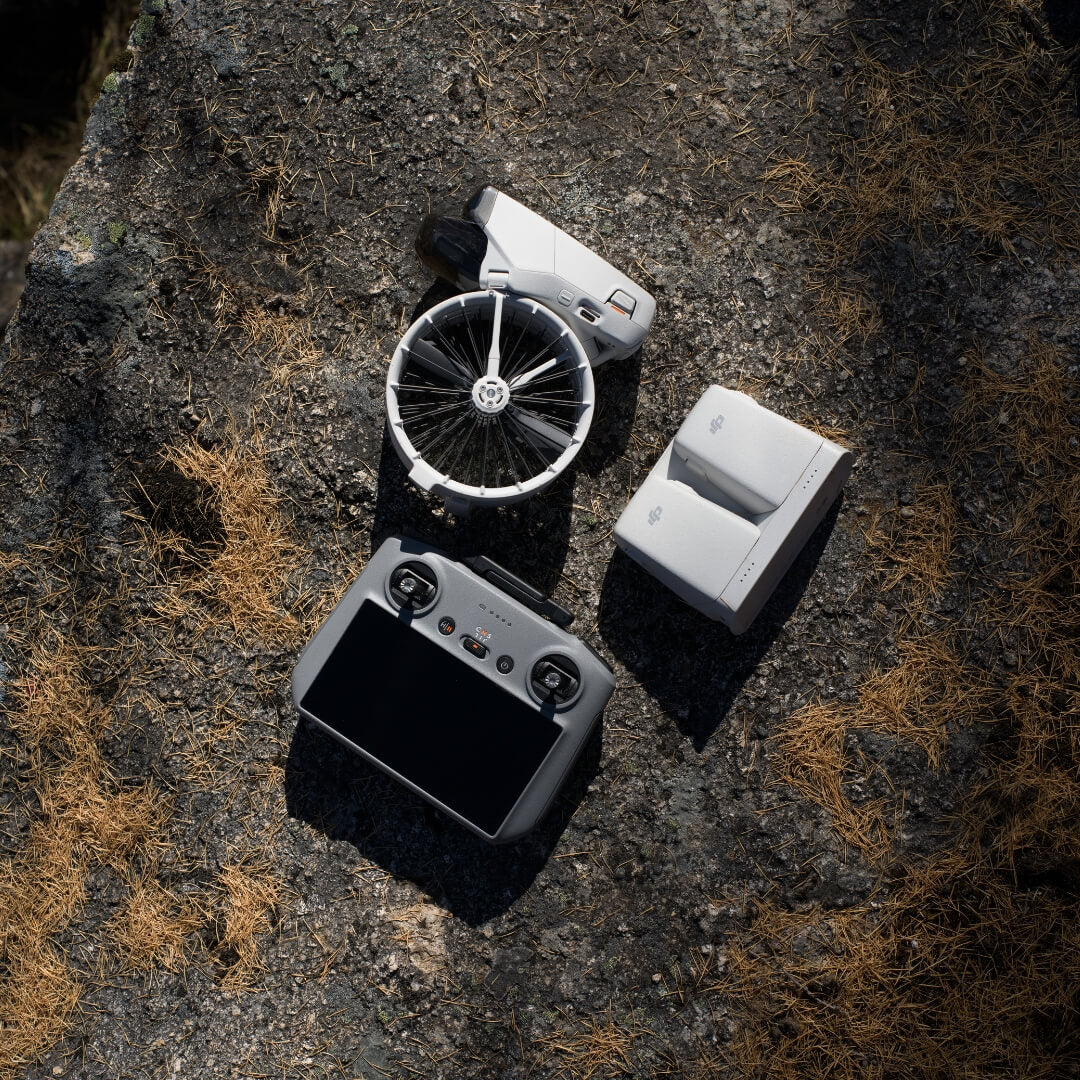 DJI Flip drone folded with RC 2 remote controller and multiple batteries in a charging hub on a dry surface