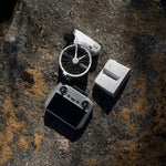 DJI Flip drone folded with RC 2 remote controller and multiple batteries in a charging hub on a dry surface