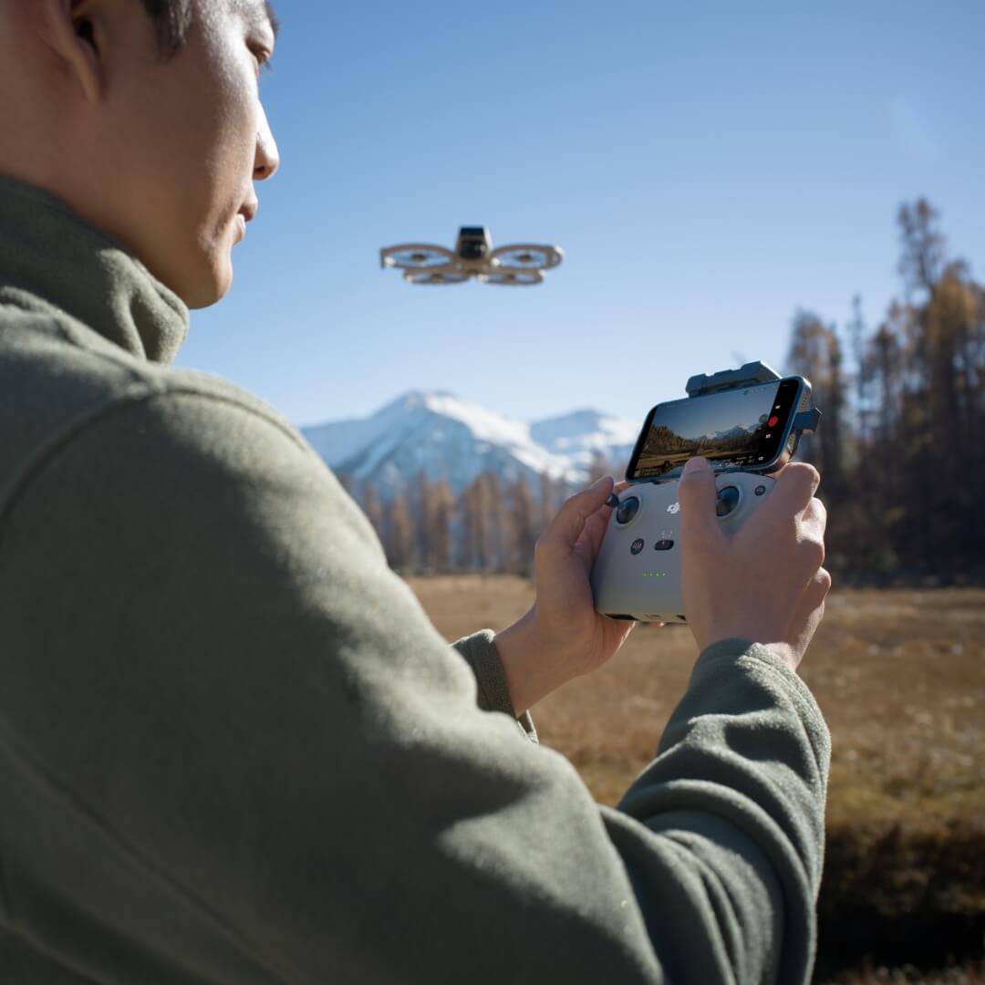 Person controlling DJI Flip drone with RC-N3 controller in a scenic outdoor setting