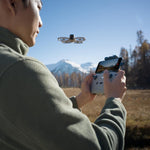 Person controlling DJI Flip drone with RC-N3 controller in a scenic outdoor setting