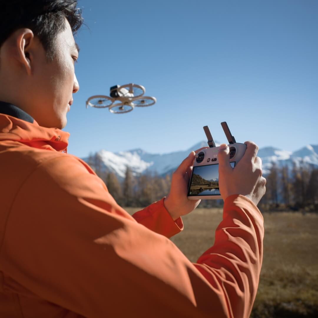 Person flying a drone with RC 2 remote controller in an outdoor setting with mountains