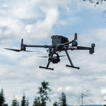 Drones flying against a blue sky with clouds