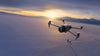 Drone flying over a snowy landscape with mountains in the background