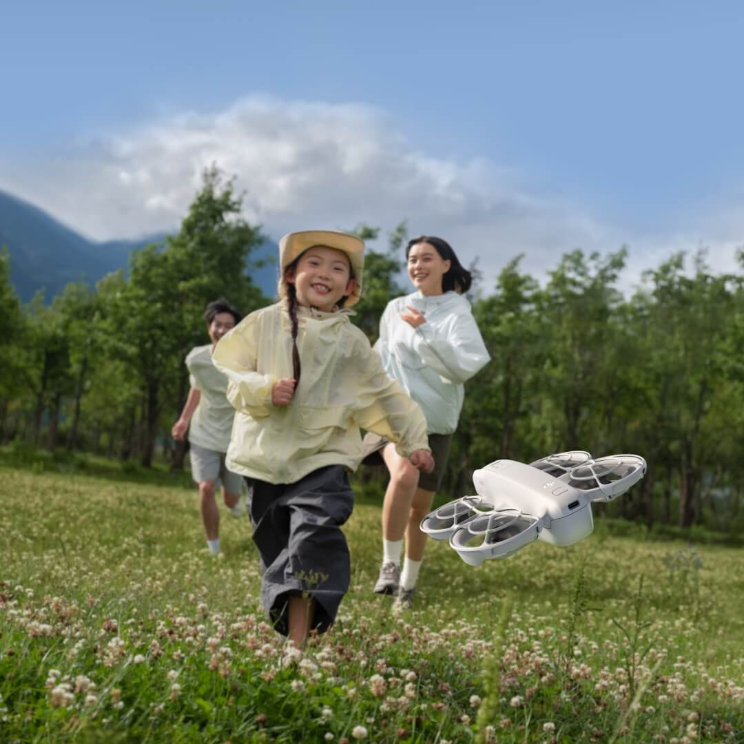 Child and parents running in a field with a Neo drone in the foreground