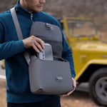 Man packing RC 2 remote controller into a grey bag with a yellow vehicle in the background